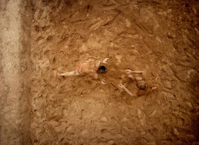 Two wrestlers practising the ancient Indian sport of Kushti in a pit they had hacked into the ground two hours before.